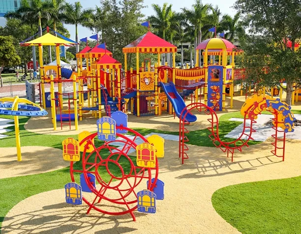 Colorful playground with slides, climbing structures, and canopy umbrellas under clear skies and palm trees.