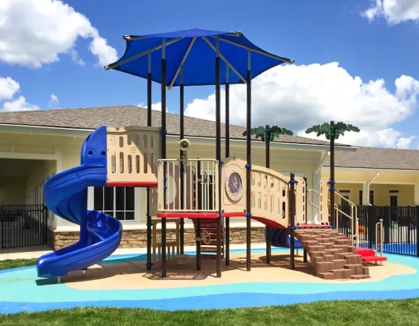 Playground structure with a blue spiral slide and shade canopy on a sunny day.