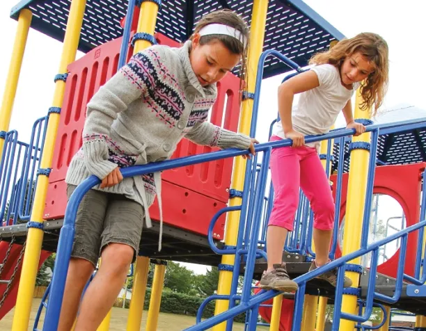 Two girls navigating blue and yellow playground steps with red panels.