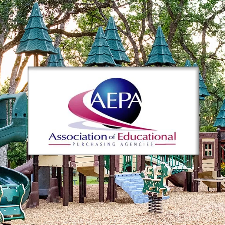Playground with green roofs and equipment surrounded by trees at sunset.