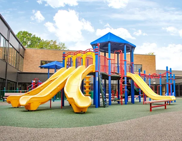 Colorful playground with multiple yellow slides and blue shaded structures on a sunny day.