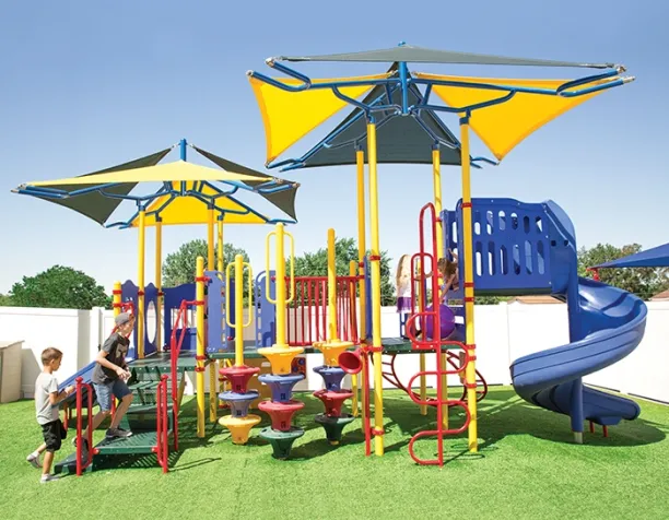 Children climbing colorful modular play structure under large yellow and blue shade canopies.