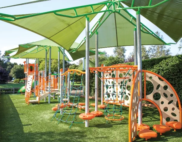 Playground with orange and green climbing structures under green shade canopies.