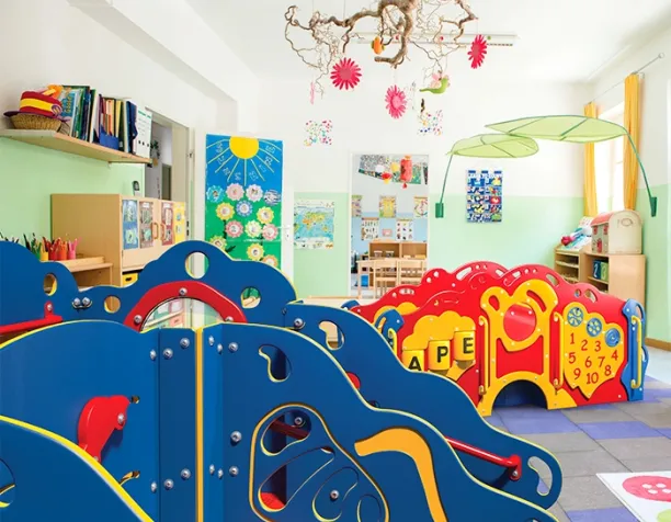 Colorful indoor play area with blue and red toddler climbing structures and educational decorations.