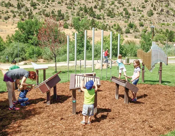 Children playing on outdoor musical instruments on a sunny day.