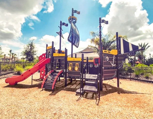 Pirate ship-themed playground set with slides and climbing ladders under a cloudy sky.