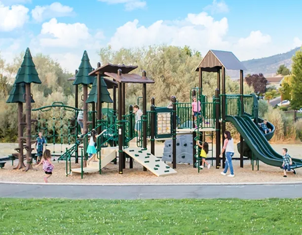 Children playing on a green and brown castle-themed playground set with slides and climbing structures.