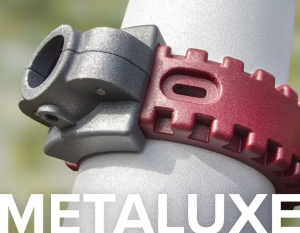 Close-up of a gray and red metal connector on a playground pole with blurred background.