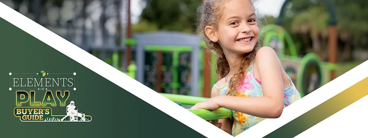 Smiling girl holding green playground equipment, with a nature background.